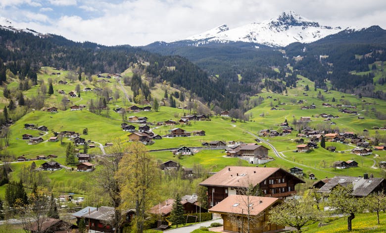 Charming village surrounded by lush green hills and snowy mountains in Interlaken, Switzerland.