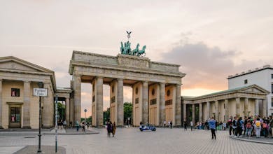 Scenic view of Berlin's Brandenburg Gate with people gathering at sunset.